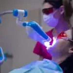 Woman in dental chair receiving teeth whitening treatment