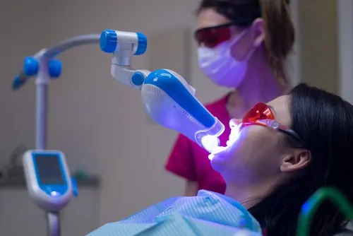 Woman in dental chair receiving teeth whitening treatment